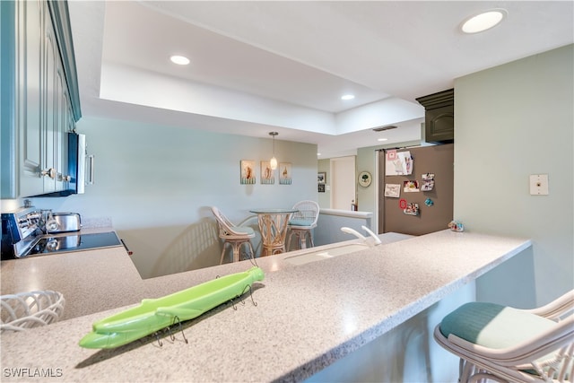 kitchen with a breakfast bar area, kitchen peninsula, sink, black range, and stainless steel refrigerator