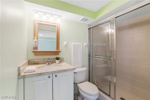 bathroom with vanity, toilet, and a shower with shower door