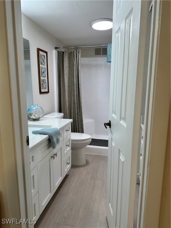 bathroom with toilet, a shower with curtain, vanity, and hardwood / wood-style flooring