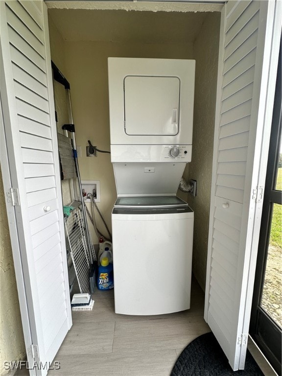 clothes washing area featuring light hardwood / wood-style floors and stacked washer and dryer