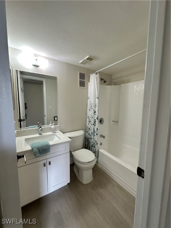 full bathroom featuring wood-type flooring, a textured ceiling, toilet, vanity, and shower / bathtub combination with curtain