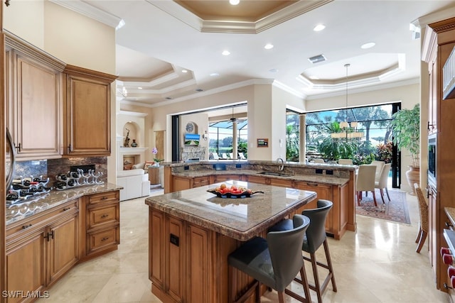 kitchen with a kitchen island, a breakfast bar area, crown molding, a raised ceiling, and tasteful backsplash