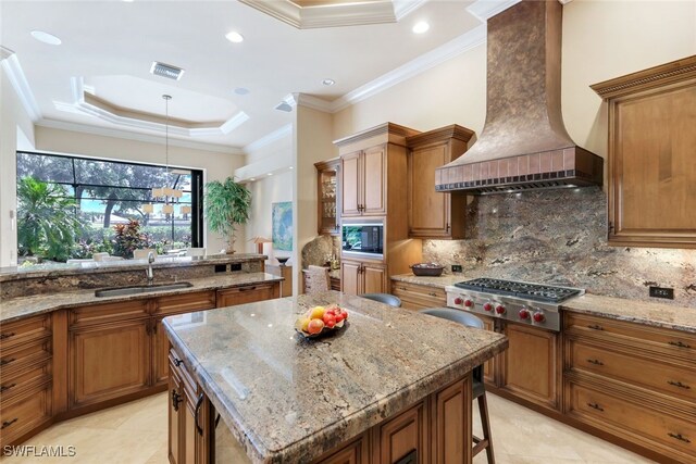 kitchen with sink, stainless steel gas cooktop, a center island, custom range hood, and ornamental molding