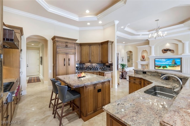 kitchen with light stone countertops, sink, a tray ceiling, a large island, and ornamental molding