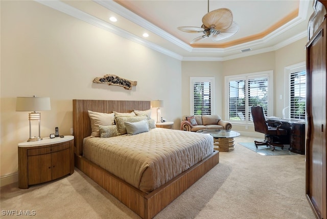 carpeted bedroom with crown molding, a tray ceiling, and ceiling fan