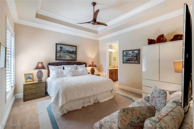 carpeted bedroom featuring ornamental molding, a raised ceiling, ensuite bathroom, and ceiling fan