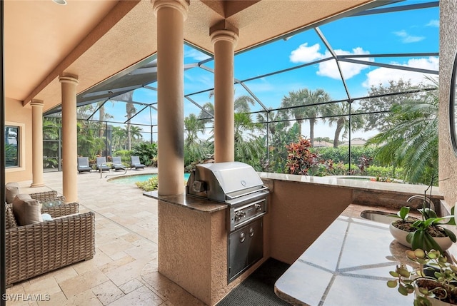 view of patio / terrace with a lanai, sink, a grill, and an outdoor kitchen