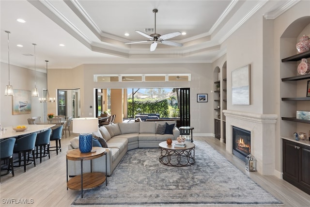 living room with built in shelves, light hardwood / wood-style flooring, ornamental molding, and ceiling fan