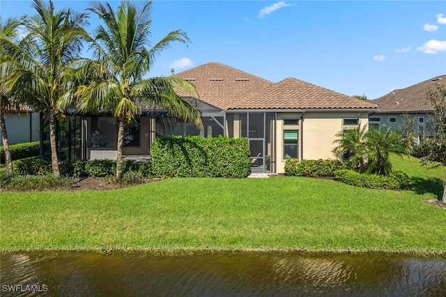 rear view of house featuring a lanai, a water view, and a yard