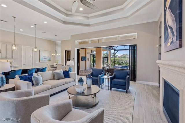 living room featuring a tray ceiling, ceiling fan, baseboards, and crown molding