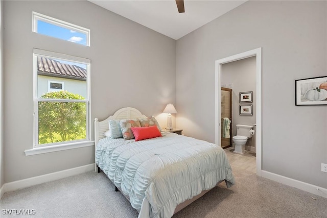 bedroom featuring connected bathroom, light colored carpet, and baseboards