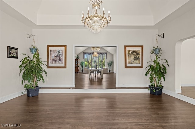 interior space with dark wood-type flooring, a notable chandelier, and a raised ceiling