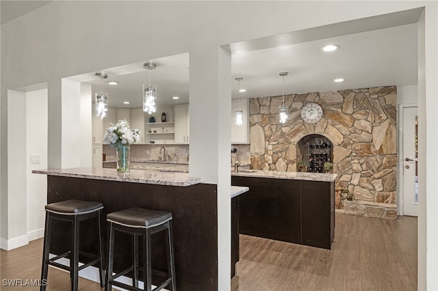 kitchen with white cabinets, hanging light fixtures, a kitchen bar, and dark hardwood / wood-style flooring