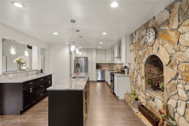 kitchen with white cabinetry, light hardwood / wood-style floors, appliances with stainless steel finishes, and hanging light fixtures