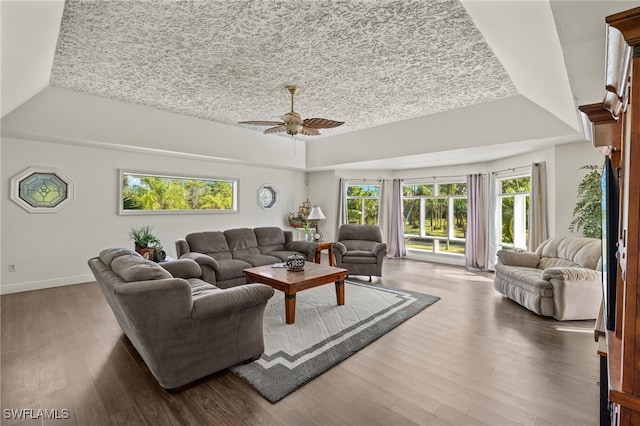 living room with ceiling fan, a raised ceiling, and dark hardwood / wood-style floors