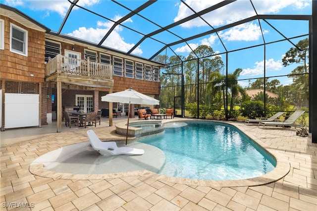 view of pool with an in ground hot tub, a patio area, and glass enclosure