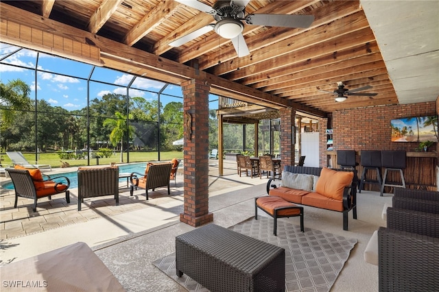 view of patio / terrace featuring ceiling fan, glass enclosure, exterior bar, and an outdoor living space