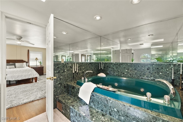 bathroom with ceiling fan, a bathing tub, and hardwood / wood-style floors