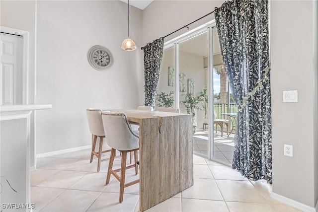 dining room with light tile patterned flooring, a high ceiling, and baseboards