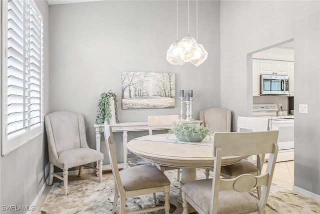 dining area with baseboards, an inviting chandelier, and a high ceiling