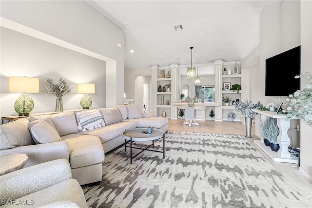 living room with a notable chandelier, high vaulted ceiling, and built in features