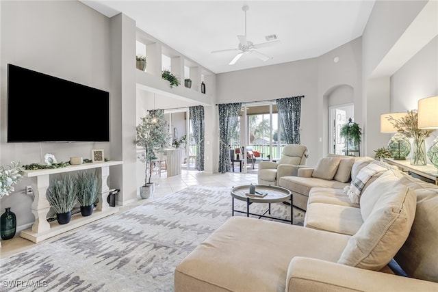 tiled living room featuring ceiling fan and a towering ceiling