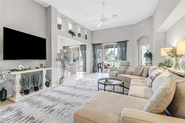 living room featuring visible vents, a ceiling fan, and a high ceiling