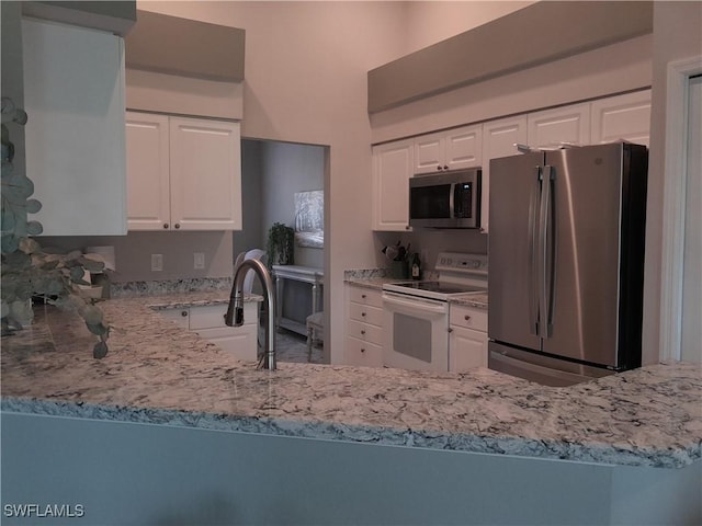 kitchen with light stone counters, a sink, appliances with stainless steel finishes, and white cabinetry