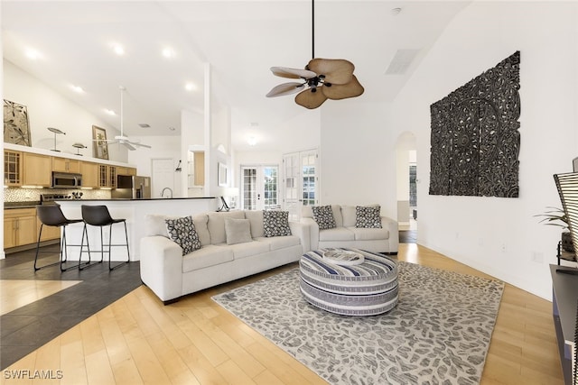 living room with light hardwood / wood-style floors, high vaulted ceiling, and ceiling fan