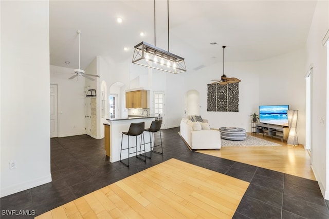 living room featuring sink, dark hardwood / wood-style floors, high vaulted ceiling, and ceiling fan