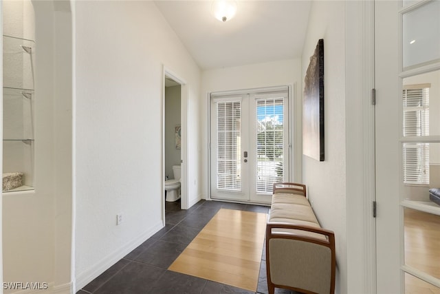 doorway with french doors, lofted ceiling, and dark tile patterned floors