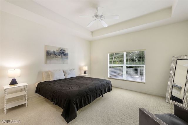 carpeted bedroom featuring ceiling fan and a raised ceiling