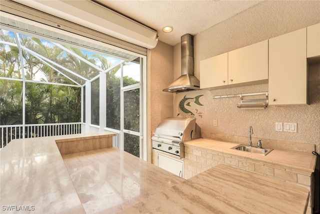 kitchen featuring sink, wall chimney range hood, a textured ceiling, and backsplash