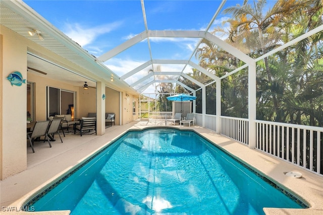 view of swimming pool featuring ceiling fan, glass enclosure, and a patio area