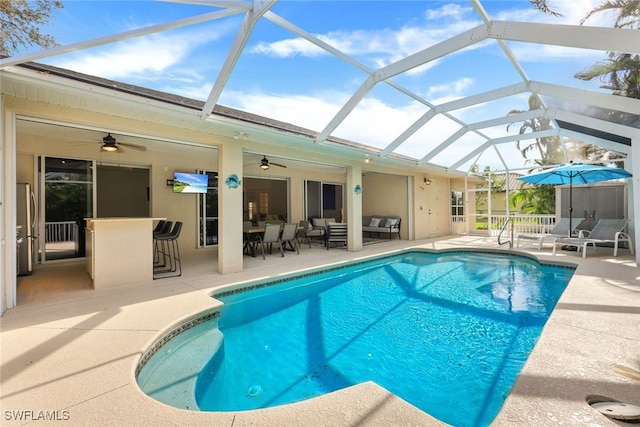 view of swimming pool featuring a patio area, glass enclosure, an outdoor hangout area, and ceiling fan