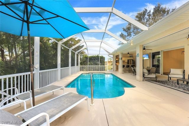 view of pool with a patio, ceiling fan, and glass enclosure