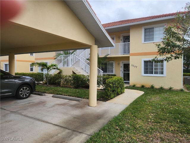 view of front of home with a front lawn, central AC, and a balcony