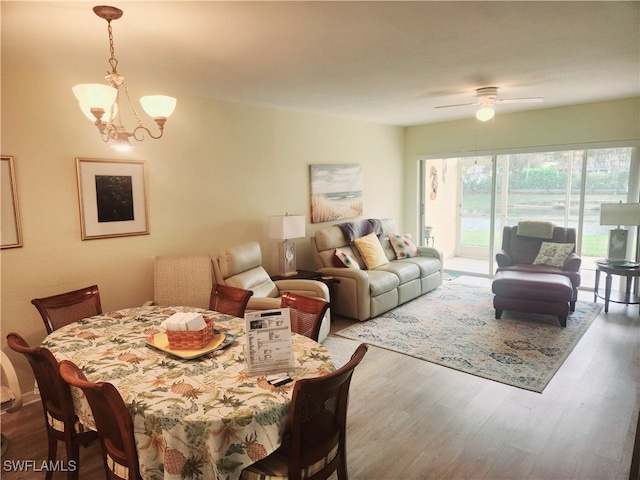 dining room with hardwood / wood-style floors and ceiling fan with notable chandelier