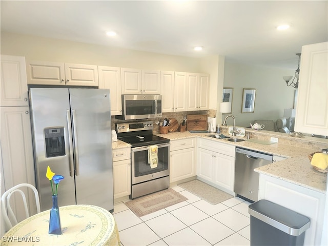 kitchen with kitchen peninsula, white cabinetry, light stone countertops, sink, and stainless steel appliances