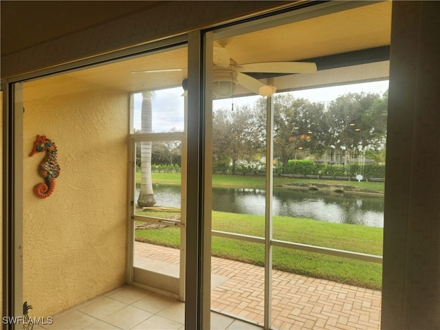 doorway with ceiling fan, a water view, and light tile patterned floors