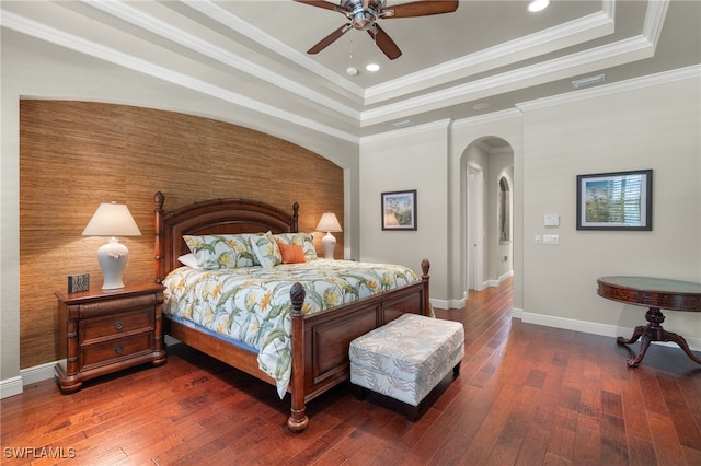 bedroom with dark wood-type flooring, a raised ceiling, crown molding, and ceiling fan