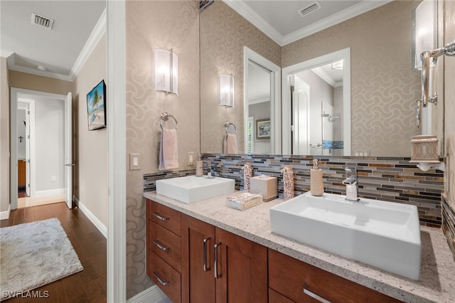 bathroom with vanity, ornamental molding, wood-type flooring, and backsplash