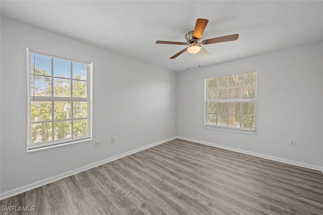 unfurnished room featuring a wealth of natural light, hardwood / wood-style flooring, and ceiling fan