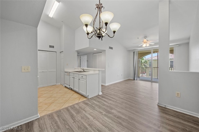 kitchen featuring light hardwood / wood-style flooring, hanging light fixtures, vaulted ceiling, white cabinetry, and ceiling fan with notable chandelier