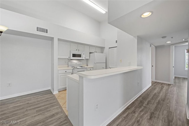 4105 Residence Dr Unit 718, Fort Myers, FL 33901 - kitchen featuring white appliances, light countertops, light wood-type flooring, baseboards, and a peninsula