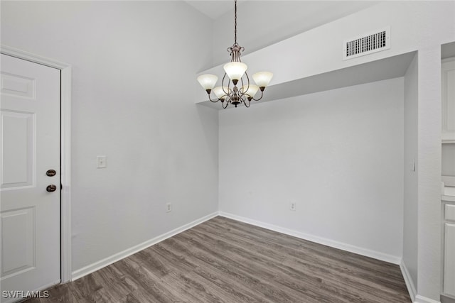 spare room featuring an inviting chandelier and dark hardwood / wood-style floors