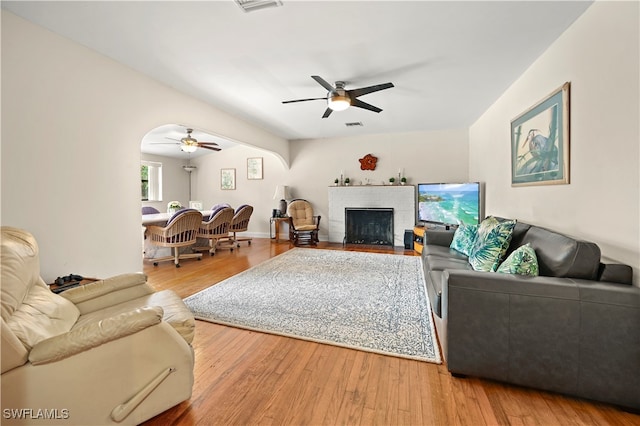 living room with a fireplace, wood-type flooring, and ceiling fan