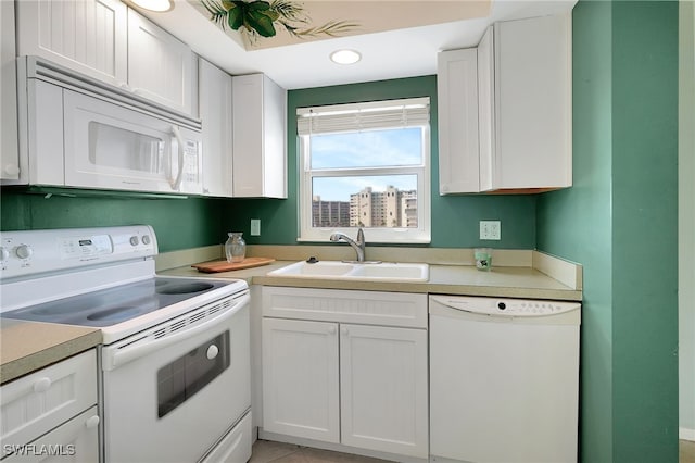 kitchen with white appliances, light tile patterned floors, sink, and white cabinets