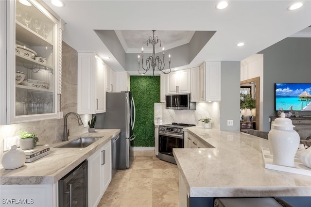 kitchen featuring kitchen peninsula, a raised ceiling, beverage cooler, stainless steel stove, and white cabinets