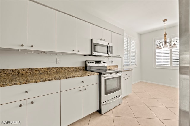 kitchen with white cabinets, appliances with stainless steel finishes, decorative light fixtures, dark stone countertops, and light tile patterned floors